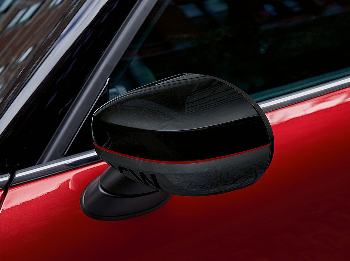 Closeup view of a black driver’s side mirror on a red MINI John Cooper Works vehicle.
