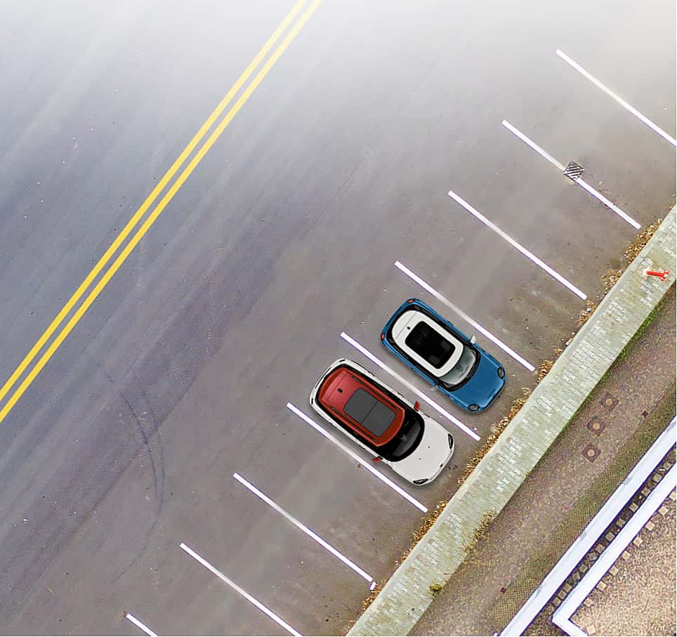 Overhead view of two MINIs, one in white and one in blue, parked side-by-side in separate parking spaces on the side of a road.