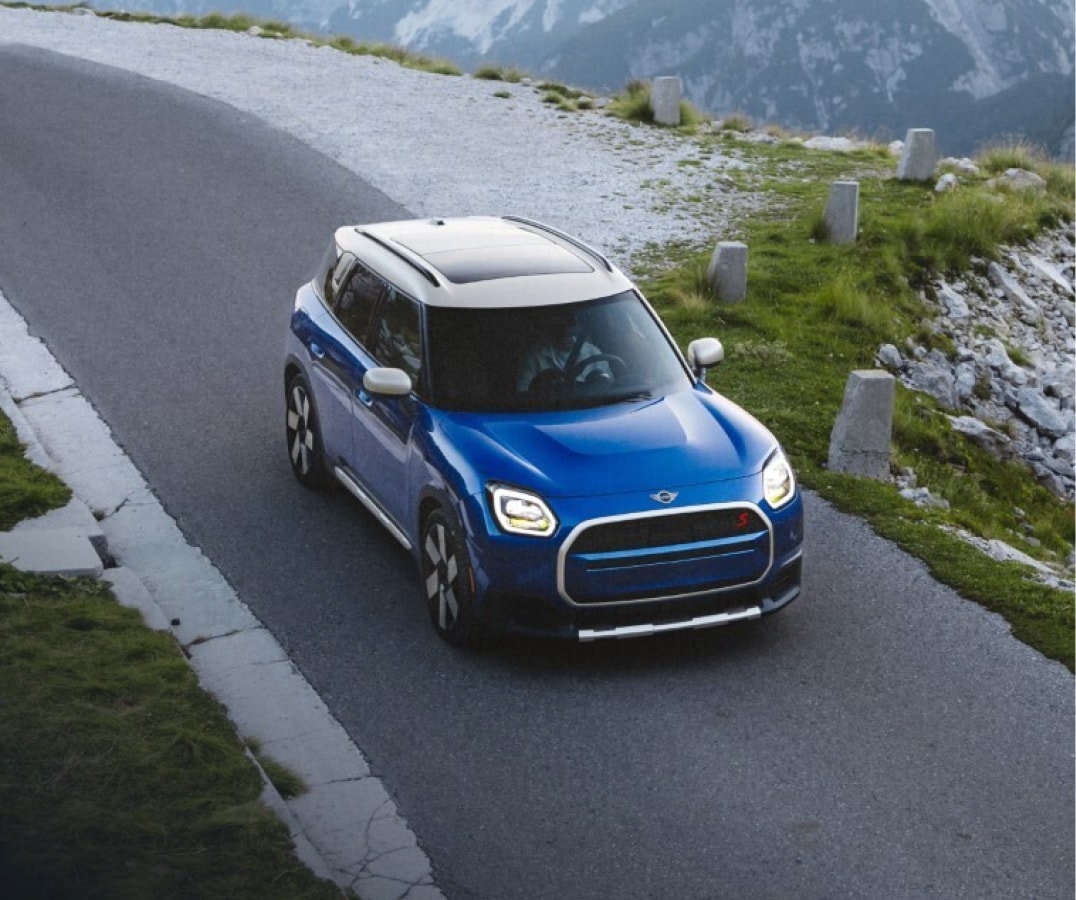 A MINI Countryman S drives on a road in a misty mountainous environment.