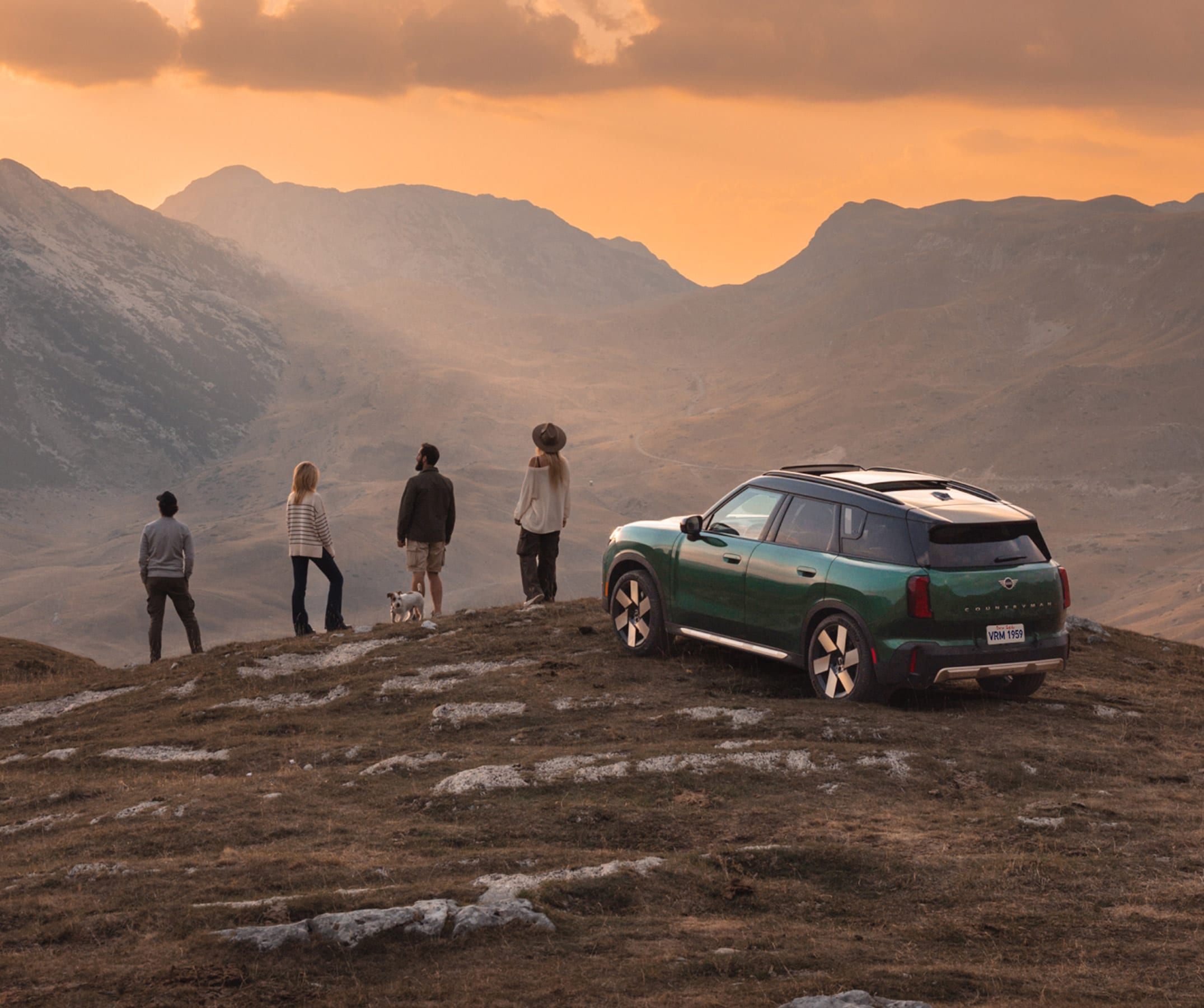 Four people look out towards mountains next to a MINI Countryman S ALL4.