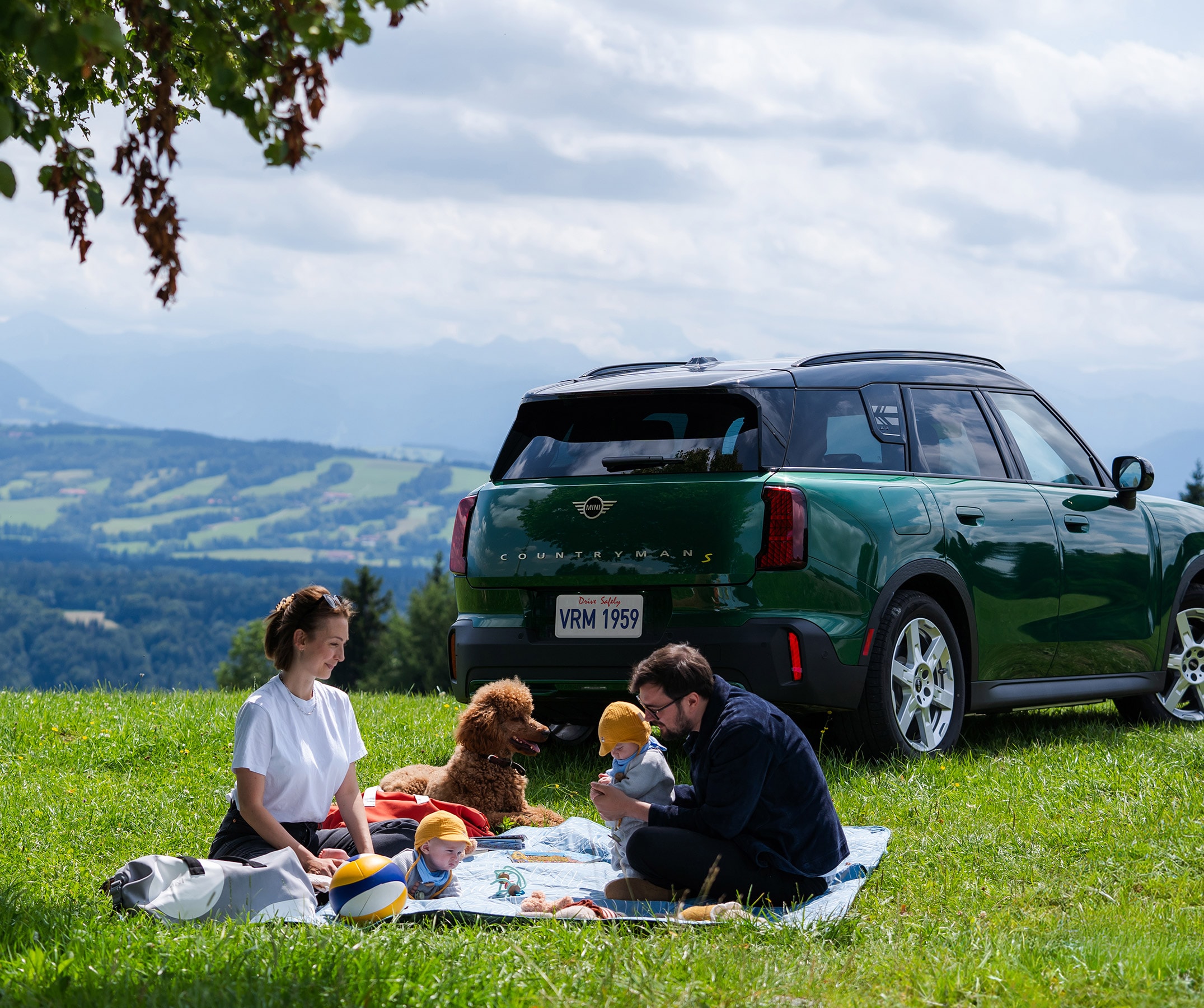 Four people look out towards mountains next to a MINI Countryman SE ALL4.