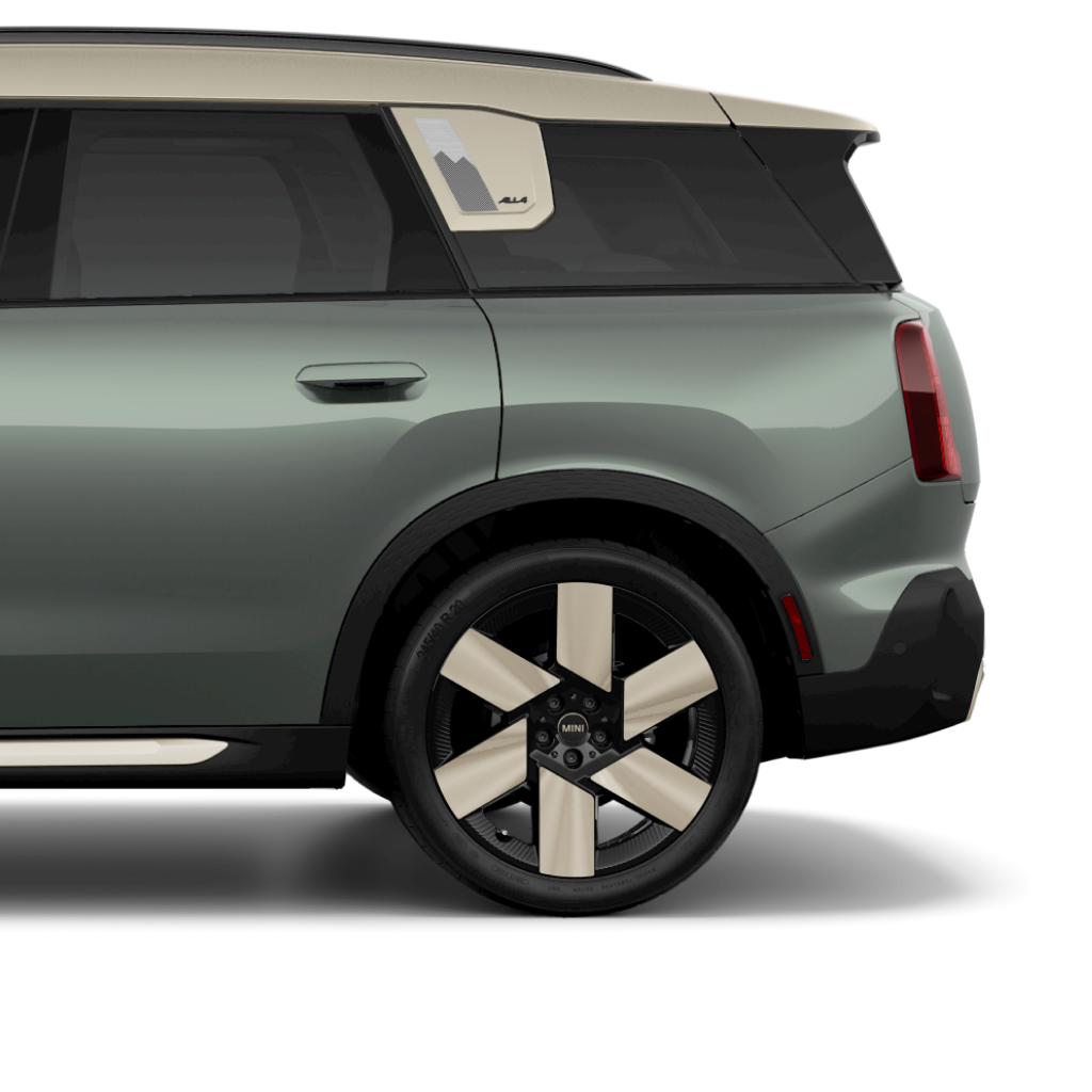 Side view of the rear of a 2025 MINI Countryman SE ALL4 in Smokey Green, parked on a blank white surface with its shadow underneath it and nothing in the background.